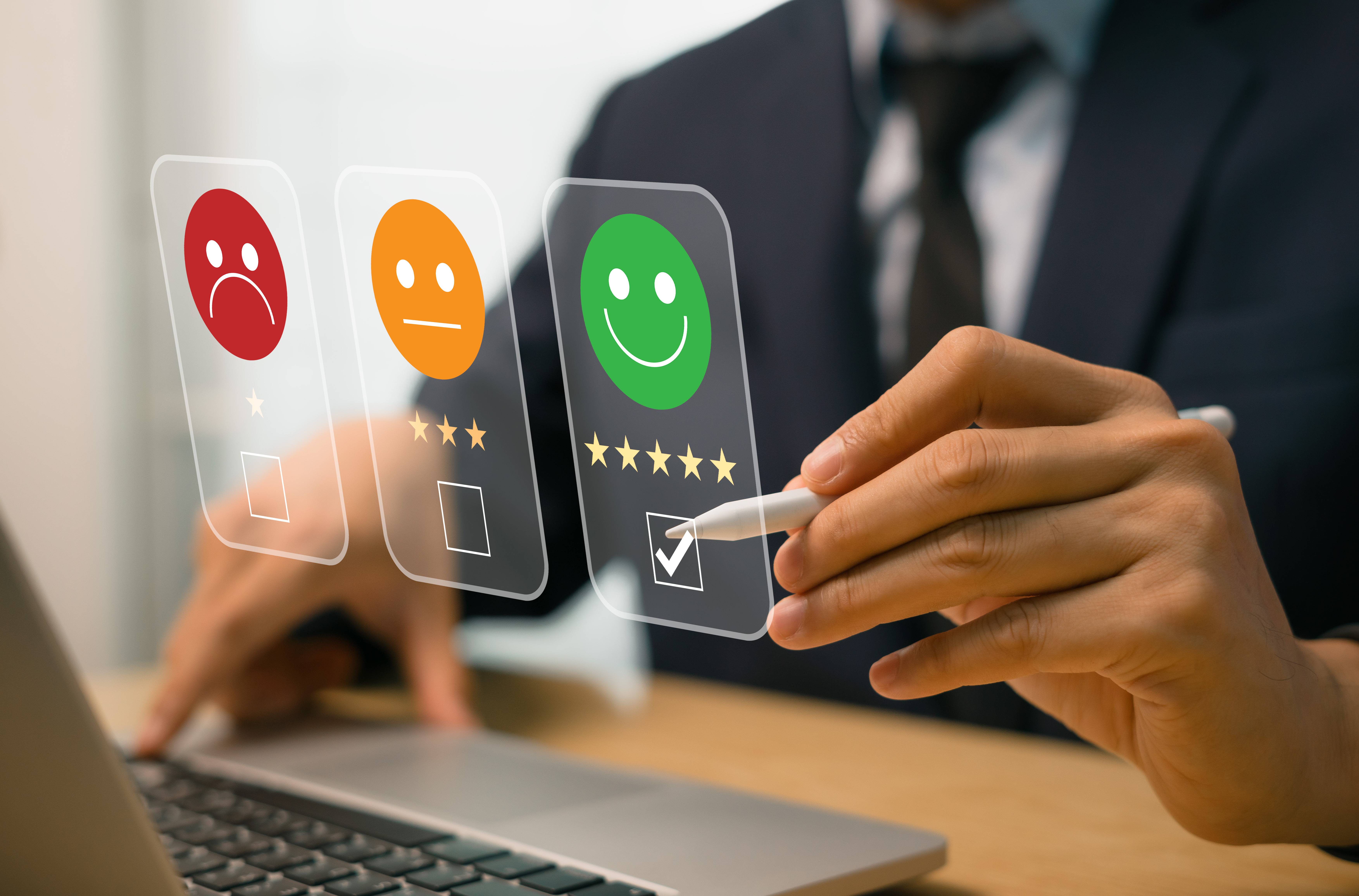 Un homme évaluant un service sur un ordinateur portable avec des émoticônes de satisfaction.