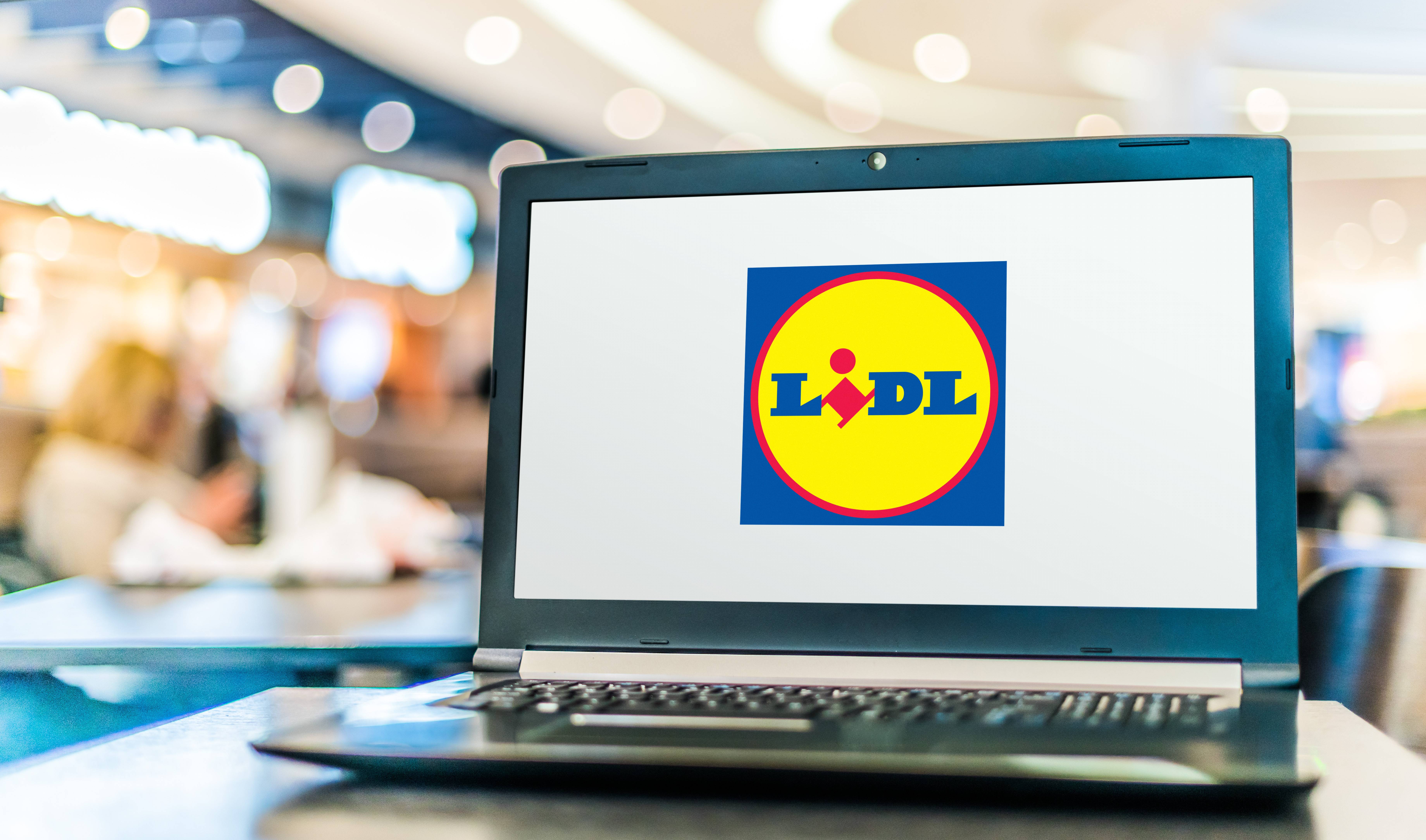 Un ordinateur portable affichant le logo Lidl sur une table dans un centre commercial.