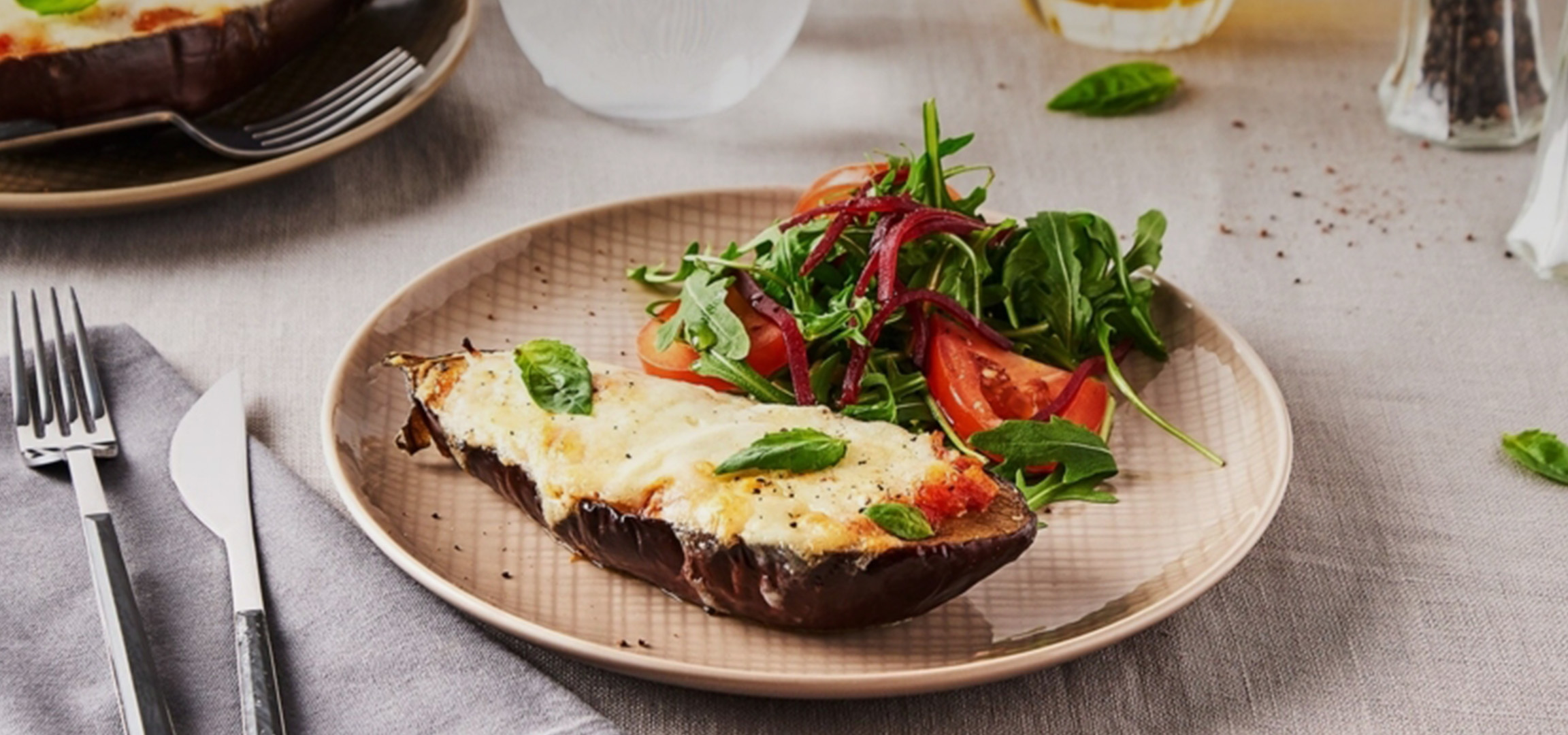Aubergine farcie au fromage et basilic, accompagnée d'une salade fraîche.