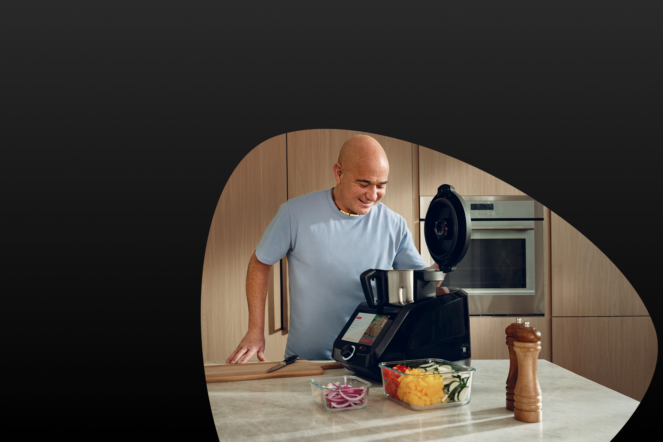 Andre Agassi prépare des légumes avec un robot de cuisine.