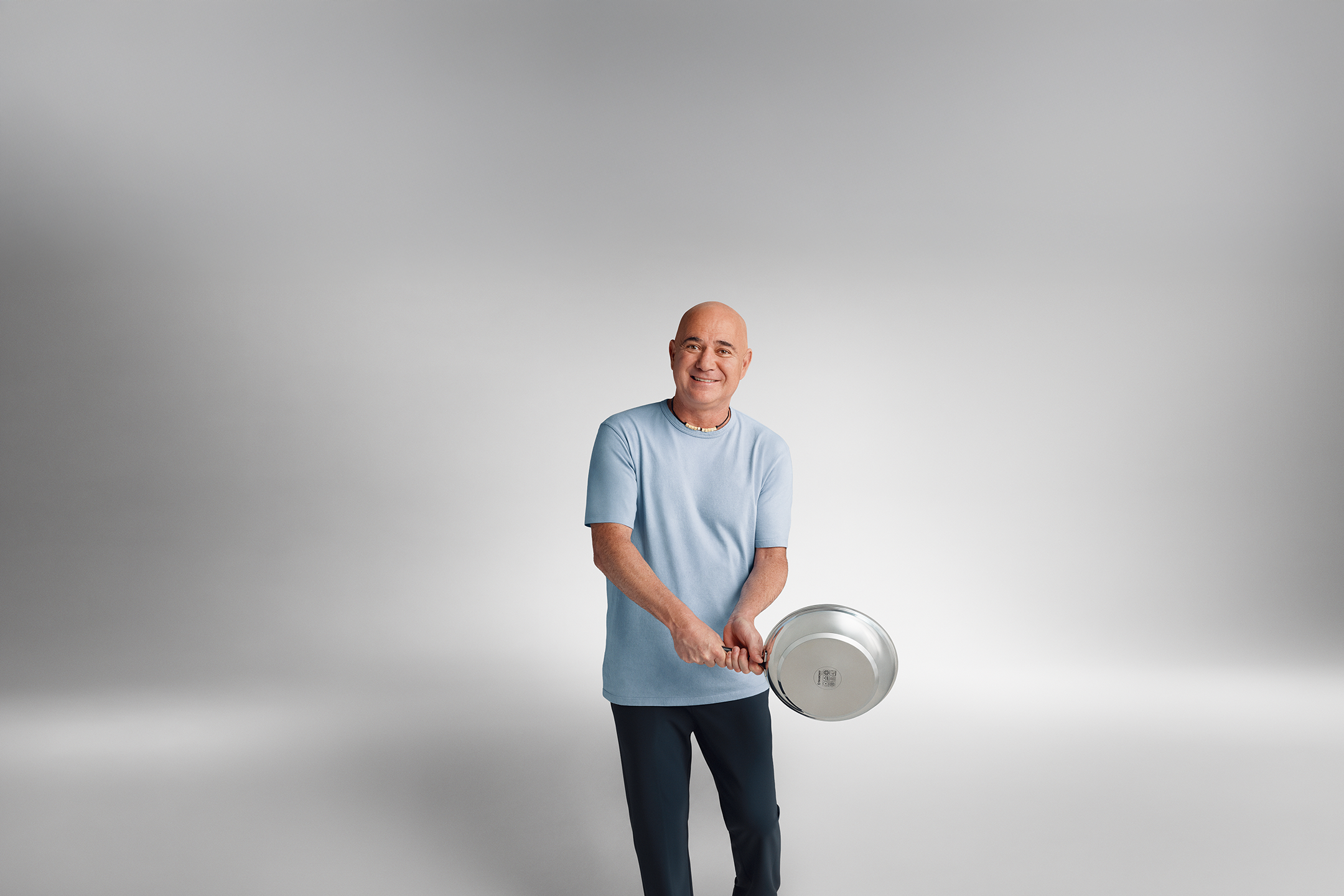 Andre Agassi, en t-shirt bleu, tient une poêle.