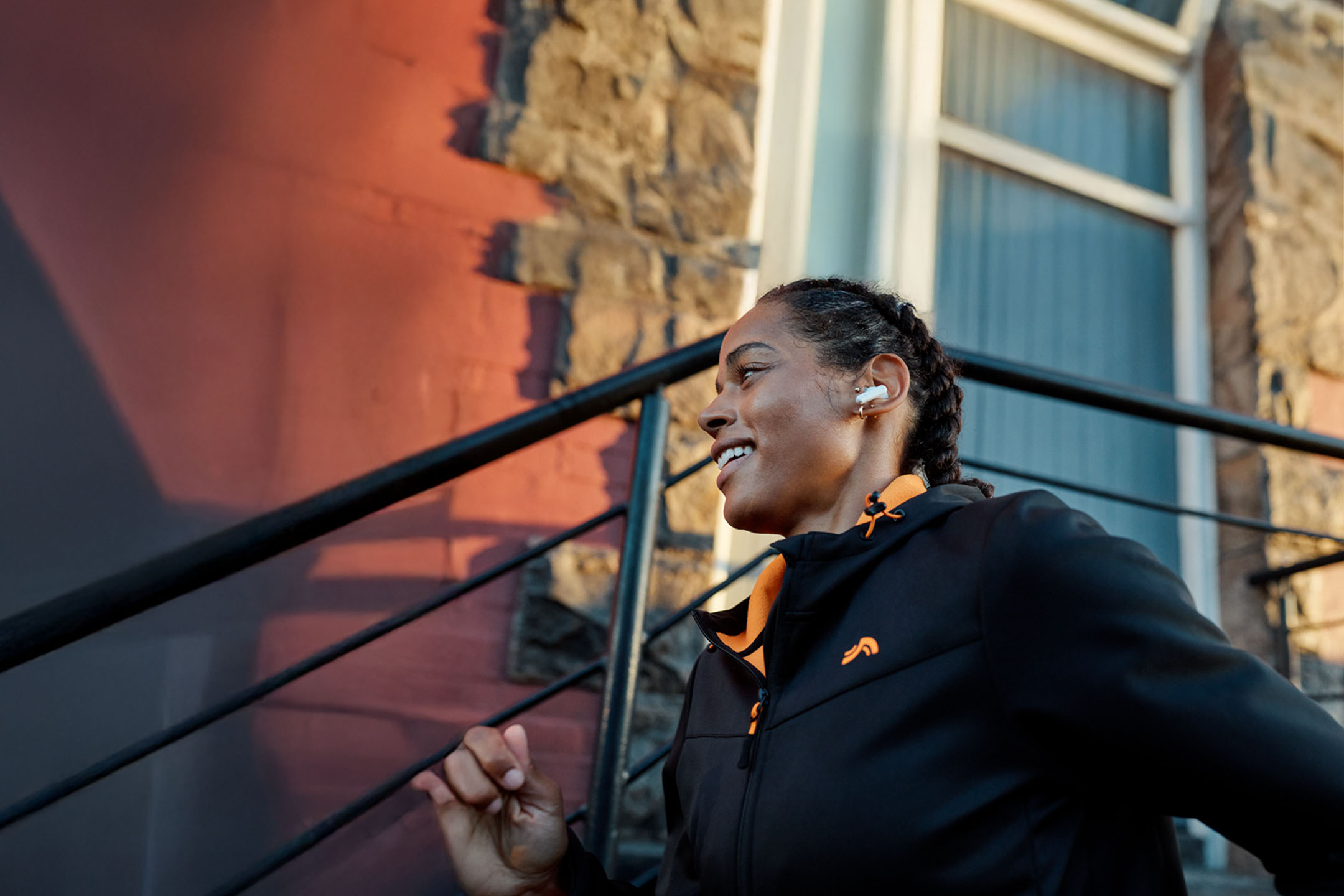 Femme courant avec des écouteurs, portant une veste.